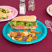 A Bermuda Blue Creative Converting paper plate with food on a table.