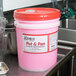 A pink bucket of Noble Chemical concentrated pot and pan soap on a counter.