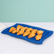 A Tablecraft blue cast aluminum rectangular platter with croissants on it.