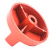 A close-up of a red plastic Tri-Star knob with a hole in it.