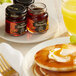 A plate of pancakes with butter and Dickinson's Pure Maple Syrup on a table.