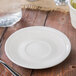 An ivory embossed china saucer with utensils on a table.