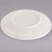 An ivory saucer with an embossed rim on a gray surface.