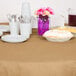 A table with plates, cups, and bowls covered by a Creative Converting Glittering Gold table cover.