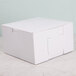 A 7" x 7" x 4" white bakery box on a marble surface.