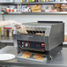 A woman using a Hatco TQ-1800 Toast Qwik Conveyor Toaster to toast bread.