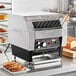 A Hatco TQ-400H conveyor toaster on a counter with a stack of bread.