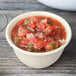 A Diamond Ivory melamine bowl filled with salsa on a wood table.