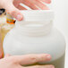 A person holding a Carlisle white plastic container with a white bottle cap.