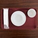 A red Cambro rectangular tray with a bowl, cup, and napkins on it.