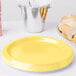 A stack of Creative Converting Mimosa Yellow paper plates.