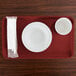 A red rectangular Cambro tray with a bowl and a cup and a napkin.