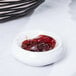 A stack of Carlisle butter dishes holding red jelly on a table.