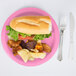 A Creative Converting candy pink paper plate with a sandwich and potato chips on it.