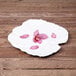 A white Elite Global Solutions melamine platter with pink petals and green leaves.