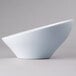 A close-up of an Elite Global Solutions white melamine bowl with a curved bottom.