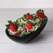 An Elite Global Solutions black melamine oval bowl filled with salad and strawberries.