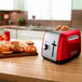 A red and silver KitchenAid toaster on a counter with bread in it.