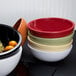 A black melamine bowl filled with oranges on a table.