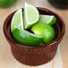 A Tablecraft maroon speckle cast aluminum souffle bowl filled with lime slices on a table.