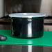 A Carlisle black plastic crock with lid on a green cutting board.