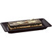 A rectangular Tablecraft midnight speckle cast aluminum platter with a rectangular chocolate cake on it.