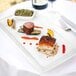 A Tuxton white rectangular china plate with food on it on a table.