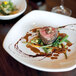 A Tuxton square white china pasta plate with a steak and mushrooms on it.