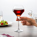 A hand holding a Chef & Sommelier wine glass filled with red wine.