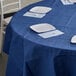 A table with white plates and forks on a navy blue tablecloth.