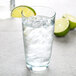 An Arcoroc highball glass filled with water, ice, and a slice of lime.