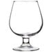 An Arcoroc brandy glass with a small amount of brandy in it.