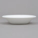 An Arcoroc white opal glass fruit dish on a gray surface.
