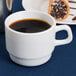 An Arcoroc white cup of coffee and a plate of pastries on a blue table.