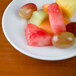 A Tuxton white porcelain mini pasta bowl with a watermelon slice on it.