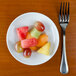 A Tuxton porcelain mini pasta bowl filled with fruit on a table.