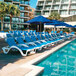 A pool with blue chairs and umbrellas, one with a blue umbrella.