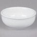 A white Tuxton China sauce dish on a gray surface.