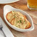 A white Tuxton oval dish with food in it.