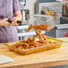 A woman using a Carlisle amber plastic food pan to hold fried chicken.