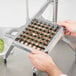 A person holding a Nemco 1/2" x 1/2" metal grid over a vegetable.