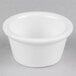 A close-up of a white Tuxton ramekin on a gray surface.