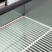 A white coated wire shelf for a back bar refrigerator.