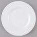 An Arcoroc white glass plate with a white rim on a gray surface.