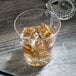 A Thunder Group plastic starburst rocks glass filled with ice and amber liquid on a wood surface.