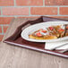 A mahogany plastic room service tray holding a plate of french toast with strawberries and powdered sugar.