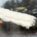 A hand using an Unger Original StripWasher with a white fluffy sleeve to clean a window.