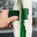 A hand holding a green fabric sleeve with a white towel inside.