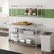 A stainless steel table with two chrome wire undershelves and two chrome wire overshelves, used for kitchen storage and prep.