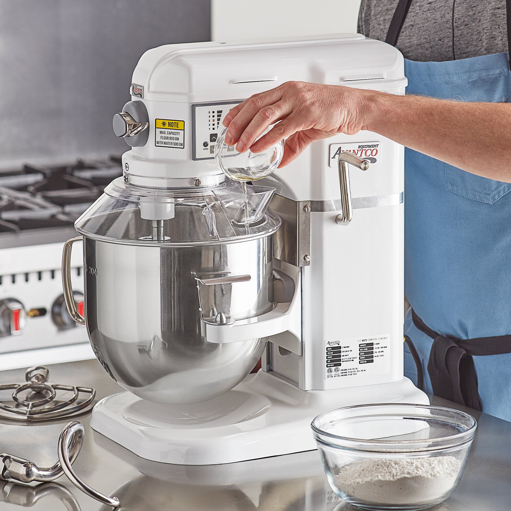 A person pouring oil into the bowl of an 8-quart Avantco stand mixer.